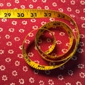 Yellow tape measure on vintage red fabric