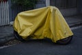 Yellow tarp cover over a parked motorcycle on the street