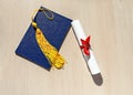 Yellow tassel from graduation cap, blue diploma and paper scroll tied with red ribbon with bow on beige wooden background Royalty Free Stock Photo