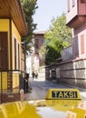 Yellow Taxi cab roof sign with TAKSI turkish word. Auto was parking on the narrow old Antalya street. Unfocused couple walking