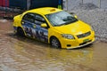 Yellow taxi cab stuck in the rain water in Bangladesh