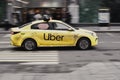 Yellow taxi car with the UBER logo fast moving on the street. Rapid ast and inexpensive means of getting around the city Royalty Free Stock Photo