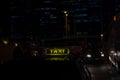 Yellow taxi sign on cab car at evening or night in the city street