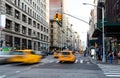 Yellow taxis driving down the street on Fifth Avenue through the busy intersections in Midtown Manhattan New York City