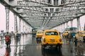 Yellow taxis and motorcycle are running on the road inside Howrah Bridge in the afternoon with rain in Kolkata, India