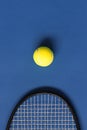 Yellow tennis ball and black racket on blue background. Color of the year 2020, vertical format photo. Active lifestyle concept