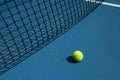 Yellow tennis ball is laying near black net. Royalty Free Stock Photo