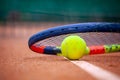 Yellow tennis ball and racket lie on the clay court Royalty Free Stock Photo