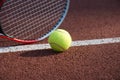 Yellow tennis ball and racquet on hard court surface Royalty Free Stock Photo