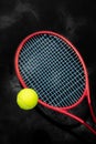 Yellow tennis ball with red racket on a black background