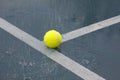 Yellow tennis ball on T line on rainy tennis court