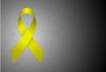 Yellow textile ribbon emblem of fight against suicide. Gray sad background similar to concrete. Place for text or