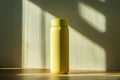 A yellow thermos bottle stands on a surface, illuminated by soft light and shadows Royalty Free Stock Photo