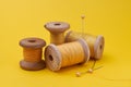 Yellow threads on wooden spools, pins with yellow heads on yellow paper background Royalty Free Stock Photo