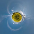 Yellow tiny planet in rapeseed field in blue sky with beautiful clouds. Transformation of spherical panorama 360 degrees. Royalty Free Stock Photo