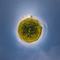 Yellow tiny planet in rapeseed field in blue sky with beautiful clouds. Transformation of spherical panorama 360 degrees. Royalty Free Stock Photo