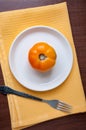 Yellow tomato in a white plate on a yellow towel, fork on the table Royalty Free Stock Photo