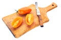 Yellow tomatoe with half slices and old knife on wooden board.