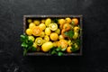 Yellow tomatoes in wooden box on black stone background. Top view. Royalty Free Stock Photo