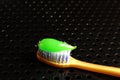 A yellow toothbrush with light bristles lies on a black metal table. And bright green toothpaste. Royalty Free Stock Photo