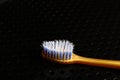 A yellow toothbrush with light bristles lies on a black metal table. Royalty Free Stock Photo