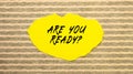 Yellow torn paper with the text ARE YOU READY on a gray-pink background Royalty Free Stock Photo