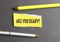 Yellow torn paper with text are you ready surrounded by pencil and pen on gray background Royalty Free Stock Photo