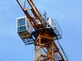 yellow tower crane boom and vertical tower body. clear blue sky. white operating cabin Royalty Free Stock Photo