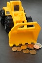 Yellow toy bulldozer, excavator carrying a lot of money - euro cent coins on dark background. Money digging, subsidies from Europe Royalty Free Stock Photo