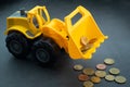 Yellow toy bulldozer, excavator carrying a lot of money - euro cent coins on dark background. Money digging, subsidies from Europe Royalty Free Stock Photo
