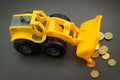 Yellow toy bulldozer, excavator carrying a lot of money - euro cent coins on dark background. Money digging, subsidies from Europe Royalty Free Stock Photo