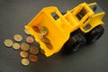 Yellow toy bulldozer, excavator carrying a lot of money - euro cent coins on dark background. Money digging, subsidies from Europe Royalty Free Stock Photo