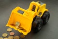 Yellow toy bulldozer, excavator carrying a lot of money - euro cent coins on dark background. Money digging, subsidies from Europe Royalty Free Stock Photo