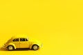 Yellow toy car on a colored background. Copy space. Children`s toy, taxi, retro car, summer, travel