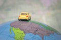 A yellow toy car is traveling around the globe. Back view The car is located on the American continent of the world map. The conce Royalty Free Stock Photo