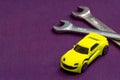 Yellow toy car and two wrenches. Cabriolet. Car service concept. Car repair. Violet blurred background. Empty space for text Royalty Free Stock Photo