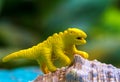 Yellow toy dinosaur on natural shell. Small puppet macro photo.