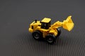 Yellow Toy Loader on Black Textured Background. Heavy machinery concept Royalty Free Stock Photo