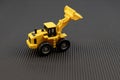 Yellow toy loader with bucket on black background. Development concept Royalty Free Stock Photo