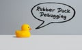 Yellow toy rubber duck and the speech balloon with the word rubber duck debugging. Software programming code explanation