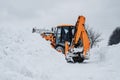 Yellow tractor cleans up snow from road. Cleaning and cleaning of roads in city from snow in winter Royalty Free Stock Photo