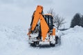 Yellow tractor cleans up snow from road. Cleaning and cleaning of roads in city from snow in winter Royalty Free Stock Photo