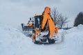 Yellow tractor cleans up snow from road. Cleaning and cleaning of roads in city from snow in winter Royalty Free Stock Photo