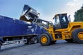 Yellow tractor dumping huge quantities of grain into the back of a articulated lorry