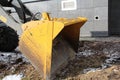 Yellow tractor knife on the ground against the background of a house in the city