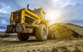 Yellow tractor loader is picking up a bucket of earth, mechanical, ladle with earth and sun Royalty Free Stock Photo