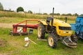 Yellow tractor with red bucket stands on the grass Royalty Free Stock Photo