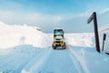 Yellow tractor removes snow from the road and clears the sidewalk in winter season. Cleaning and clearing roads after snowfalls Royalty Free Stock Photo