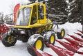 Yellow tractor seeder on winter snow