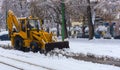 Yellow tractor with snowplow removing snow from the streets